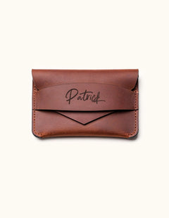 Handcrafted brown leather wallet with personalized name engraving, minimalist slim card holder design with envelope-style flap for everyday carry.