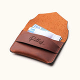 Open view of handcrafted brown leather wallet with personalized name engraving, showing credit cards inside minimalist slim card holder with envelope flap.