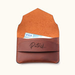 Handcrafted brown leather wallet shown open with visible suede interior, holding a credit card in the personalized slim card holder with name engraving and envelope flap design.
