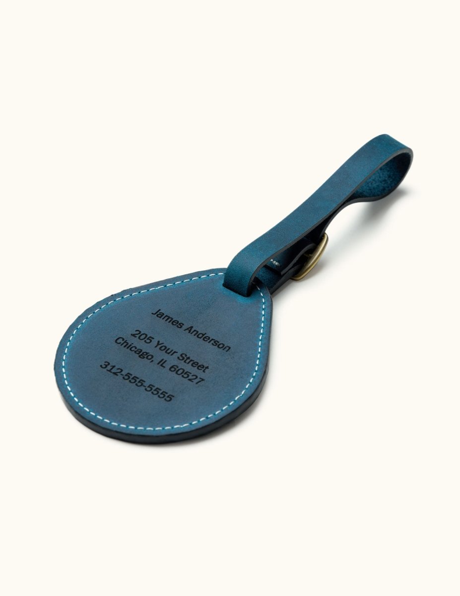 Back side of blue leather luggage tag with custom engraved name, address, and phone number