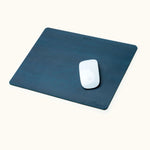 Blue personalized leather mouse pad with engraved name, shown with Apple Magic Mouse on top