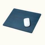 Blue personalized leather mouse pad with engraved name, shown with Apple Magic Mouse on top