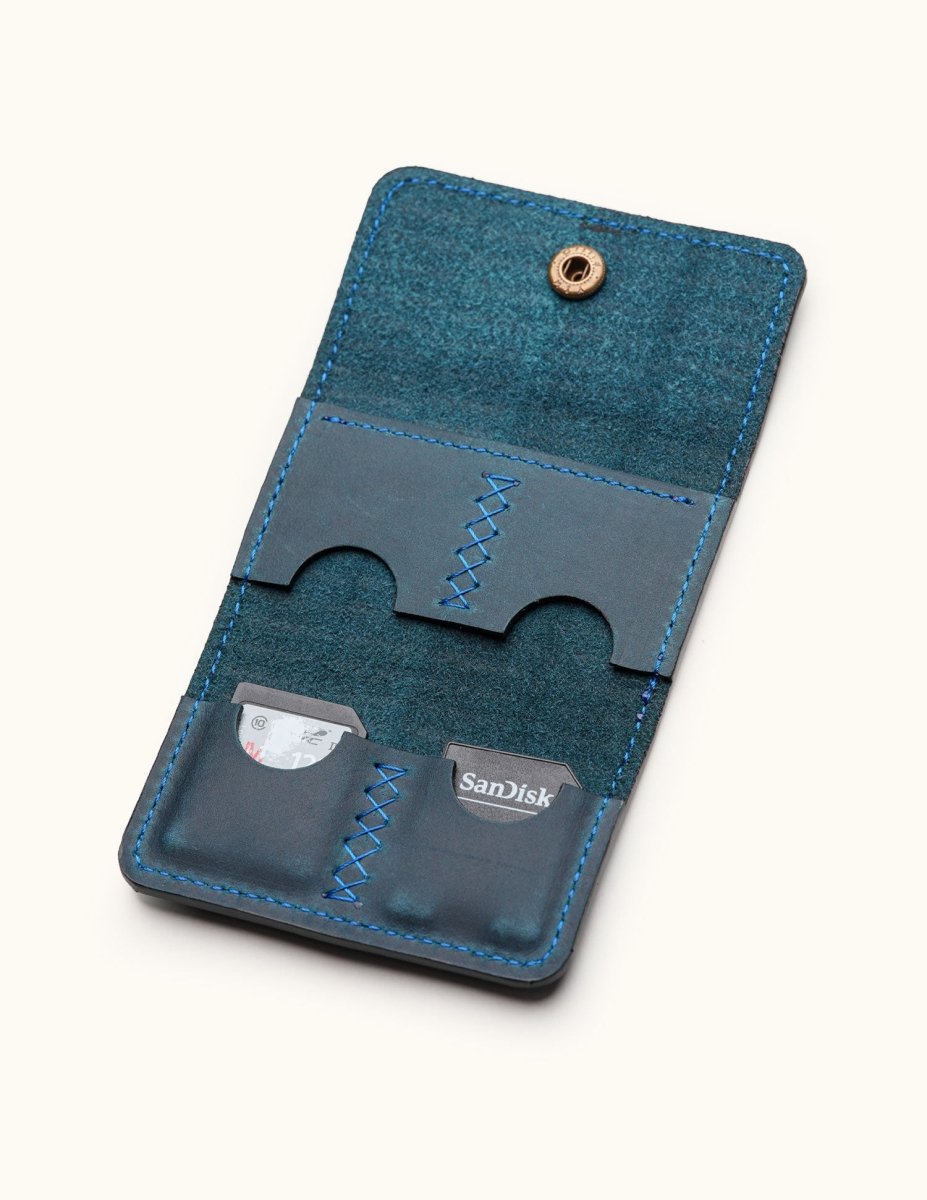 Interior view of blue leather SD card holder with four stitched compartments and snap closure, designed for photographers or tech users