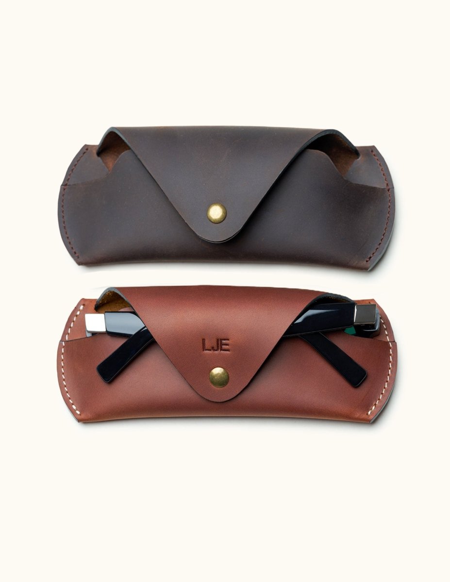 Comparison of two Crazy Horse leather sunglasses cases in brown and dark brown, one personalized and holding black sunglasses