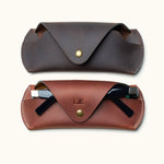 Comparison of two Crazy Horse leather sunglasses cases in brown and dark brown, one personalized and holding black sunglasses