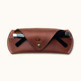 Personalized brown Crazy Horse leather glasses case with sunglasses partially inserted and snap button closure
