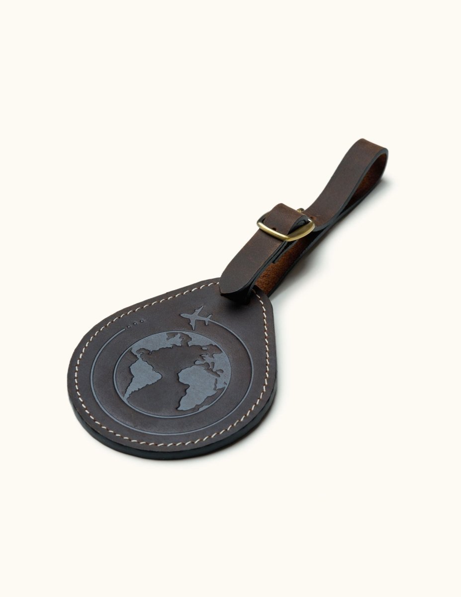 Brown leather luggage tag with embossed globe and airplane design, perfect for personalized travel gifts