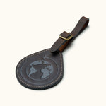 Brown leather luggage tag with embossed globe and airplane design, perfect for personalized travel gifts