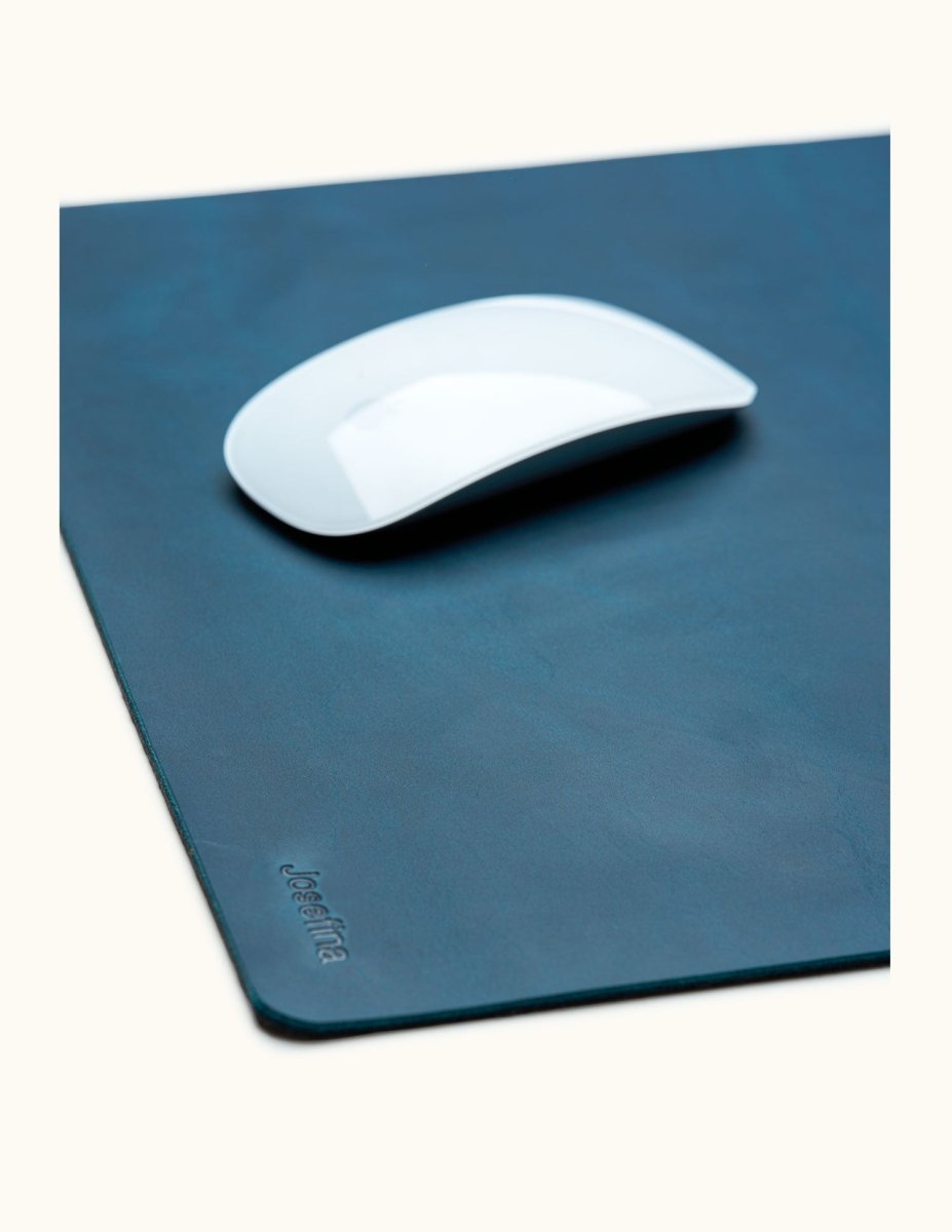 Close-up of blue leather mouse pad with engraved name Josefina and white Apple Magic Mouse