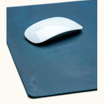 Close-up of blue leather mouse pad with engraved name Josefina and white Apple Magic Mouse