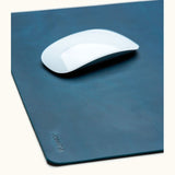 Close-up of blue leather mouse pad with engraved name Josefina and white Apple Magic Mouse