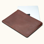 Slim full-grain leather MacBook Air sleeve in brown, customizable, shown partially open with laptop inside