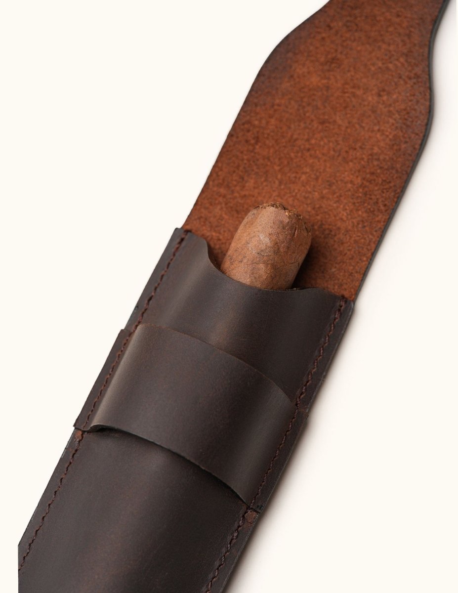 Close-up of a dark brown full-grain leather cigar case with flap open and cigar partially inserted, highlighting the craftsmanship and suede-textured inner lining