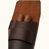 Close-up of a dark brown leather double cigar case holding two cigars, showing the suede-lined interior and precision hand-stitching