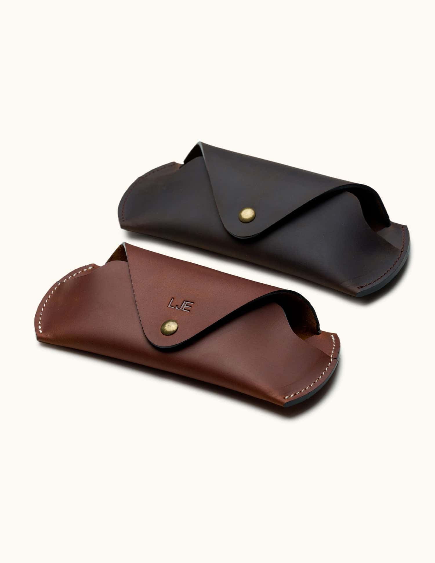 Two handcrafted Crazy Horse leather sunglasses cases in brown and dark brown, with snap buttons and personalized initials