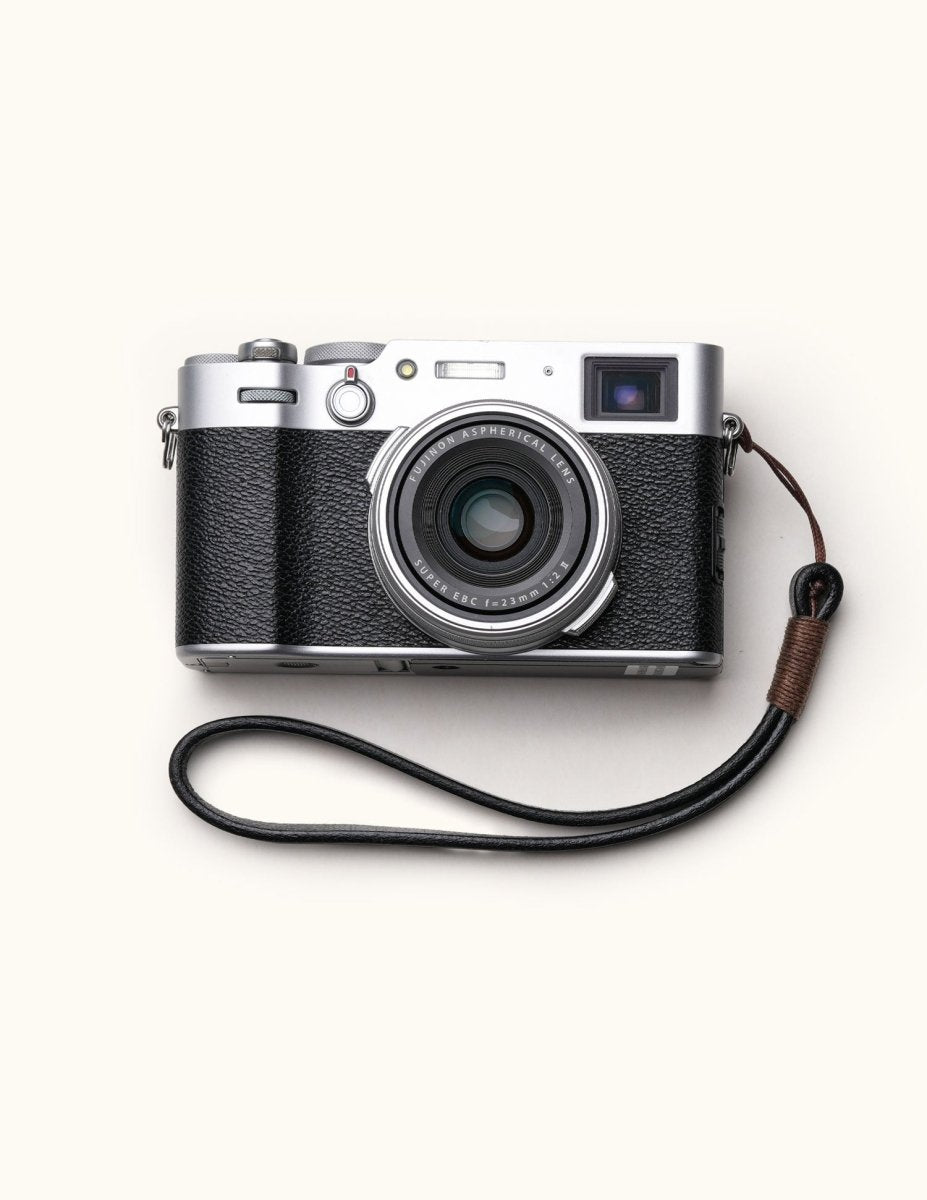 Handmade full-grain leather camera wrist strap attached to a classic Fujifilm camera, showcasing a minimalist and vintage aesthetic