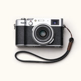 Handmade full-grain leather camera wrist strap attached to a classic Fujifilm camera, showcasing a minimalist and vintage aesthetic