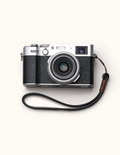 Handmade full-grain leather camera wrist strap attached to a classic Fujifilm camera, showcasing a minimalist and vintage aesthetic