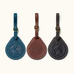 Set of three round leather luggage tags in navy, brown, and black with engraved globe and compass designs