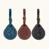Set of three round leather luggage tags in navy, brown, and black with engraved globe and compass designs