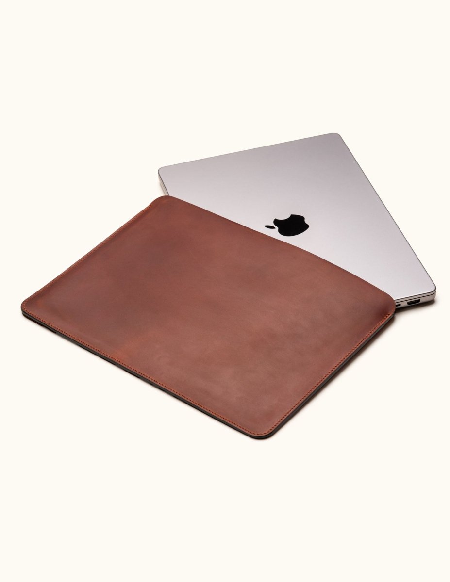 Vintage brown full-grain leather sleeve for MacBook Pro 14-inch and 16-inch, shown partially open with laptop inside
