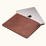 Vintage brown full-grain leather sleeve for MacBook Pro 14-inch and 16-inch, shown partially open with laptop inside
