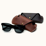 Brown and dark brown handcrafted leather sunglasses cases displayed with black sunglasses, personalized with initials