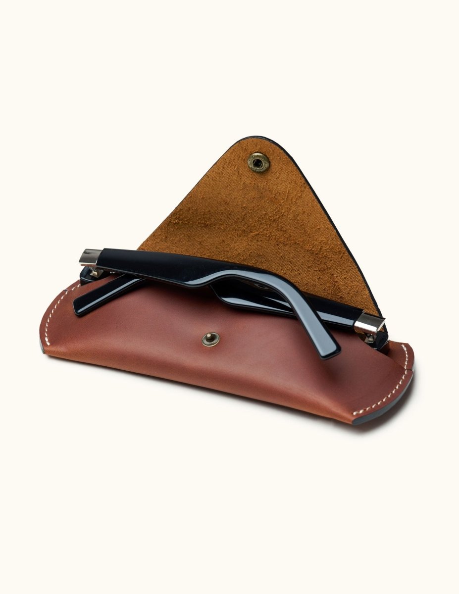 Open view of brown Crazy Horse leather sunglasses case with black sunglasses partially inserted, showing suede interior