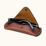 Open view of brown Crazy Horse leather sunglasses case with black sunglasses partially inserted, showing suede interior