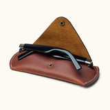 Open view of brown Crazy Horse leather sunglasses case with black sunglasses partially inserted, showing suede interior