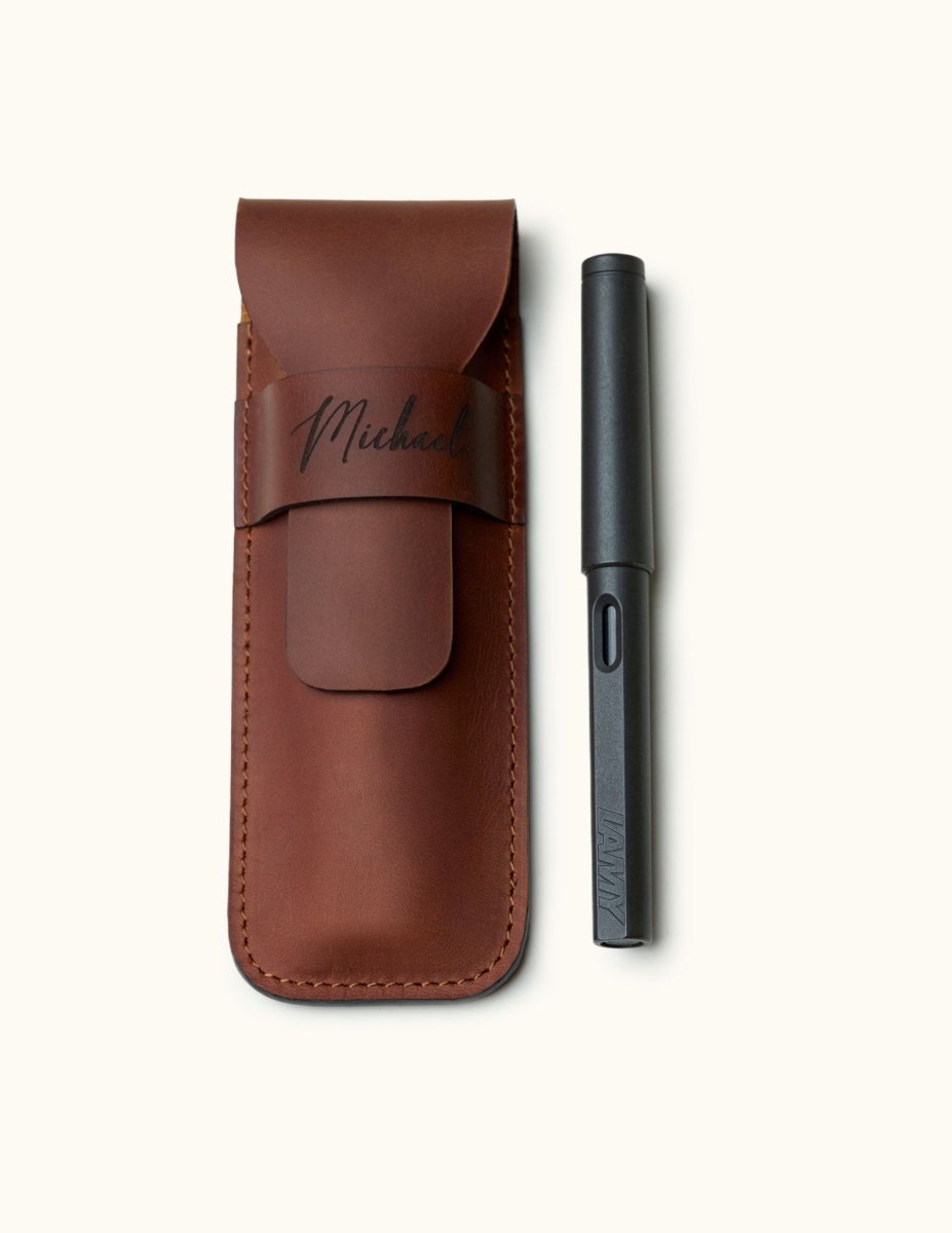 Handmade full-grain leather pen case designed for two pens, shown with a black LAMY fountain pen. Personalized with name engraving and secure flap closure