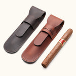 Two personalized leather cigar cases in dark brown and chestnut, one engraved with "Best Man", shown next to a single cigar. A stylish gift idea for groomsmen or cigar lovers