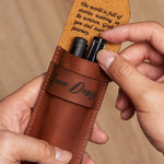 Hands holding a personalized full-grain leather pen case with two pens inside and an engraved inspirational message under the flap