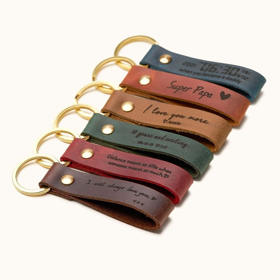 Handmade leather keychains in assorted colors with gold rings, engraved with custom messages, dates, and quotes, perfect for personalized gifts, anniversaries, and Father’s Day.