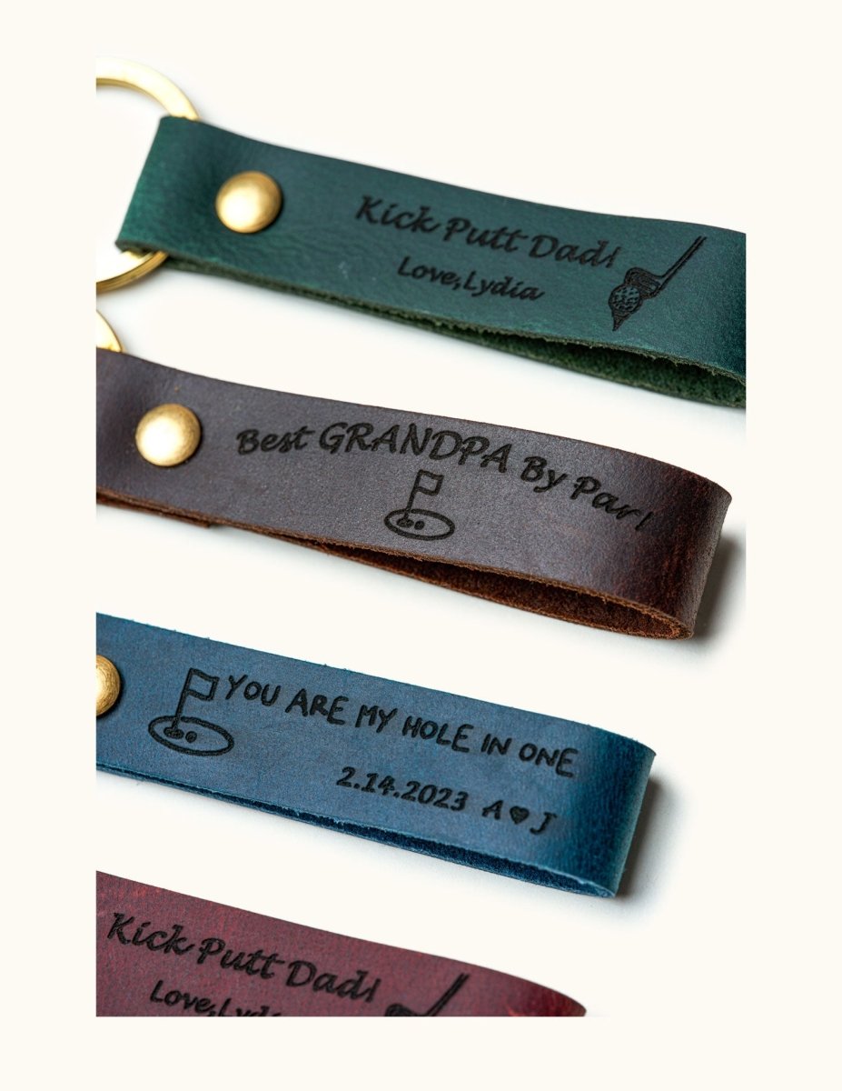 Close-up view of personalized leather keychains engraved with golf designs and sayings like “Kick Putt Dad” and “You Are My Hole In One,” custom golf gifts for dad, grandpa, and golf lovers.