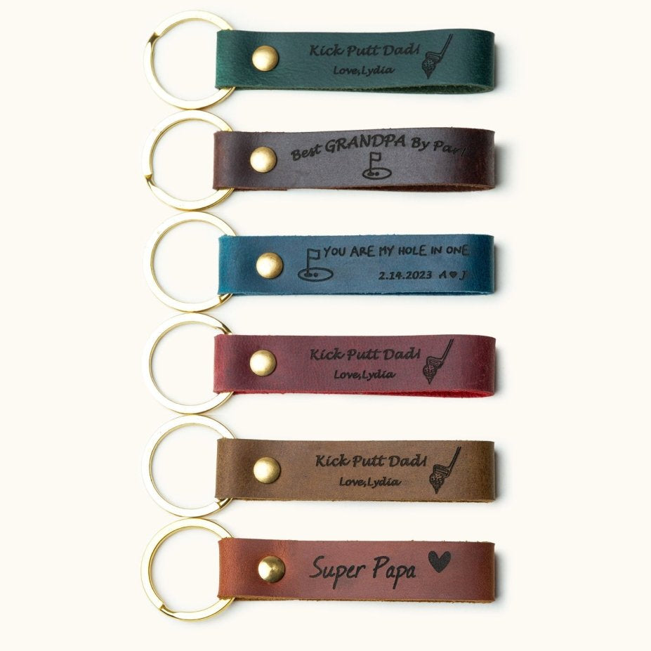 Handmade leather keychains with gold rings, engraved with golf-themed messages like “Kick Putt Dad” and “Best Grandpa,” perfect personalized gifts for golf lovers, dads, and grandpas.

