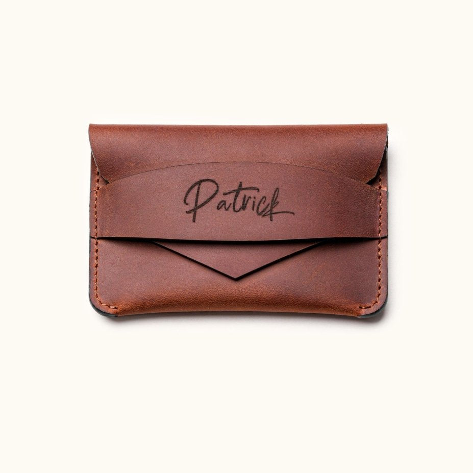 Handcrafted brown leather wallet with personalized name engraving, minimalist slim card holder design with envelope-style flap for everyday carry.