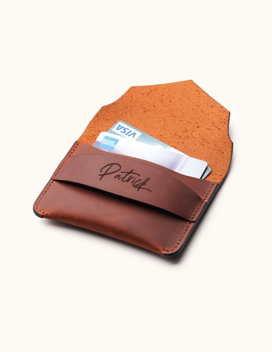 Open view of handcrafted brown leather wallet with personalized name engraving, showing credit cards inside minimalist slim card holder with envelope flap.