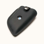 Angled view of black leather key fob cover for BMW G Series smart key with snap button and logo window