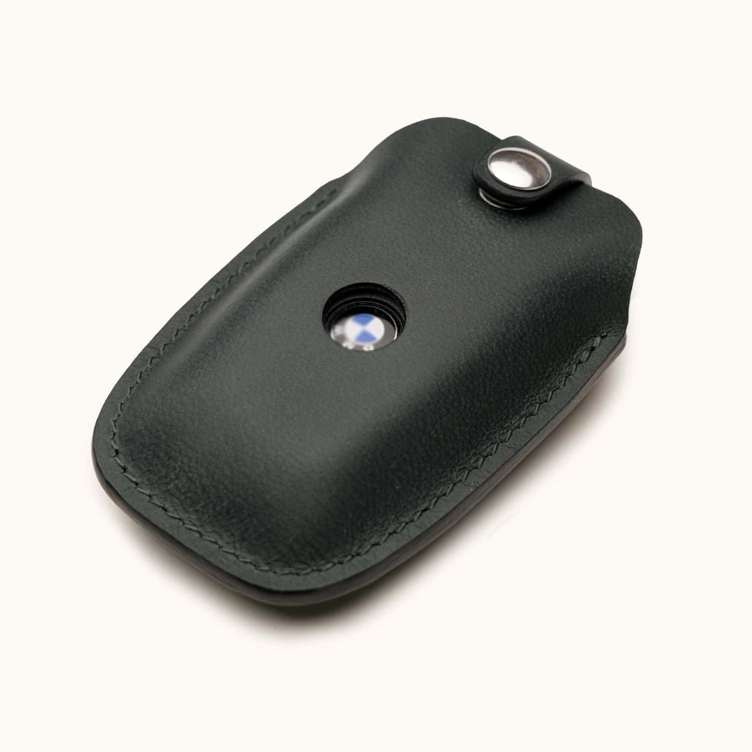 Angled view of black leather BMW key fob case with snap button and visible logo window