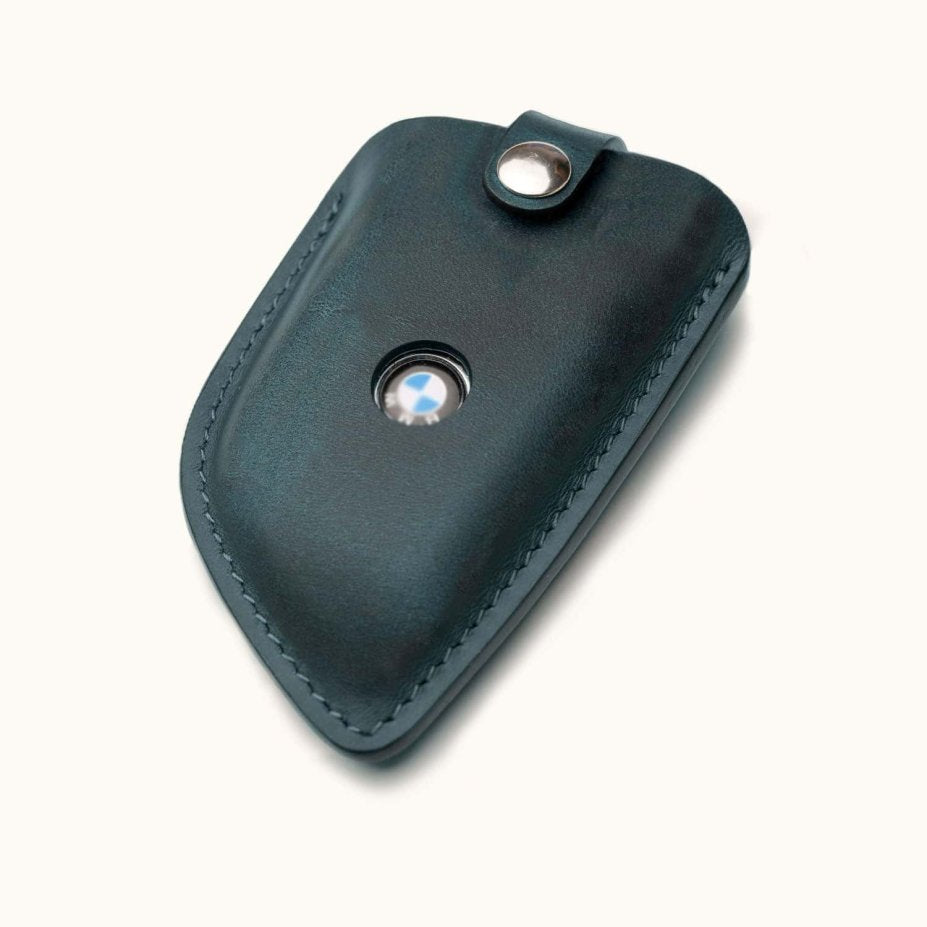 Angled view of blue leather BMW G Series smart key cover with snap button and logo window