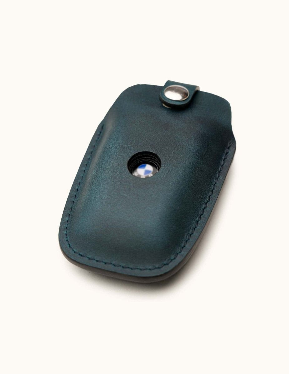 Angled view of blue leather key case for BMW smart key with snap closure and logo window