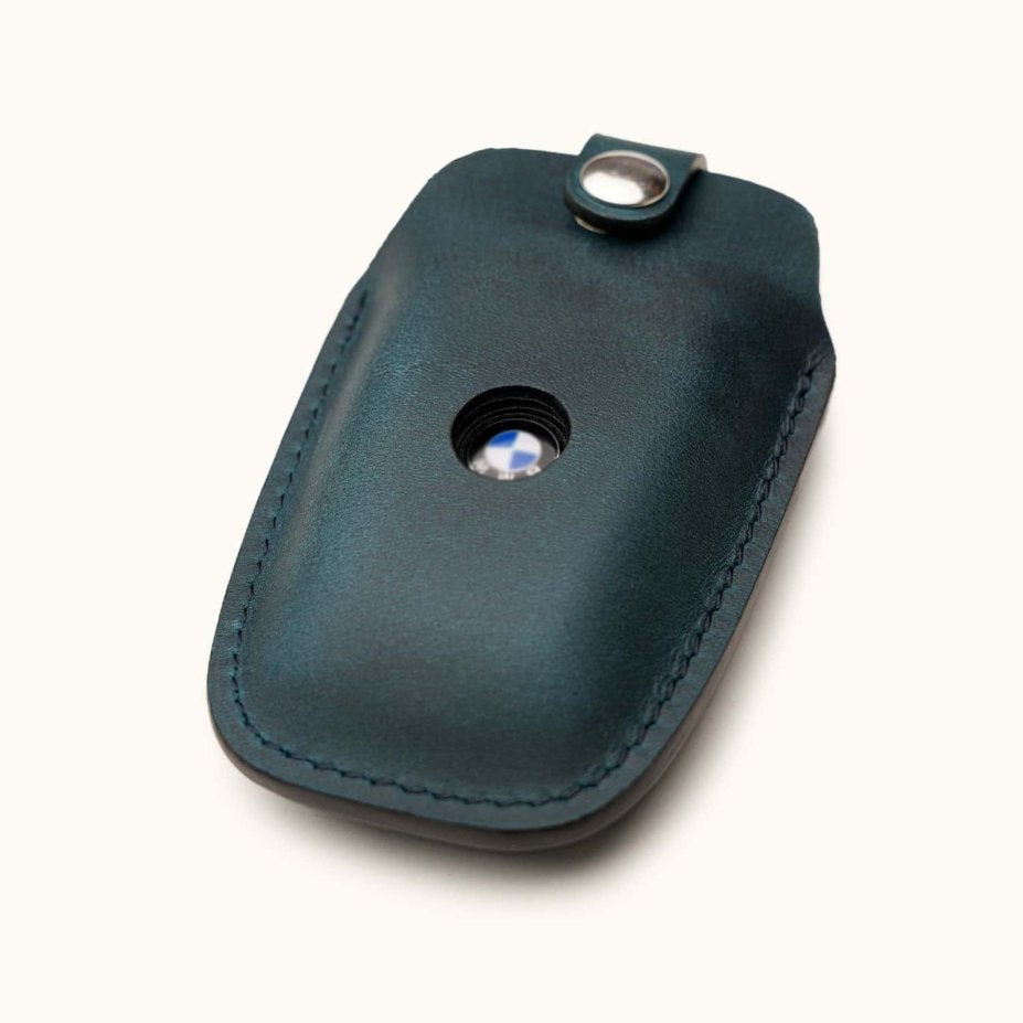 Angled view of blue leather key case for BMW smart key with snap closure and logo window