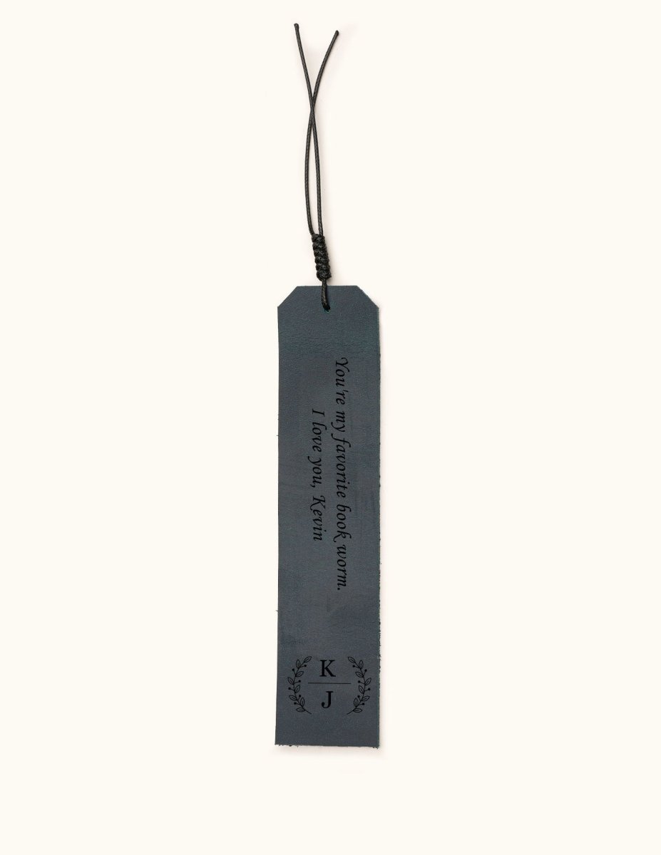 Blue leather bookmark engraved with the message "You're my favorite book worm. I love you, Kevin" and personalized initials "K | J" inside a laurel wreath design