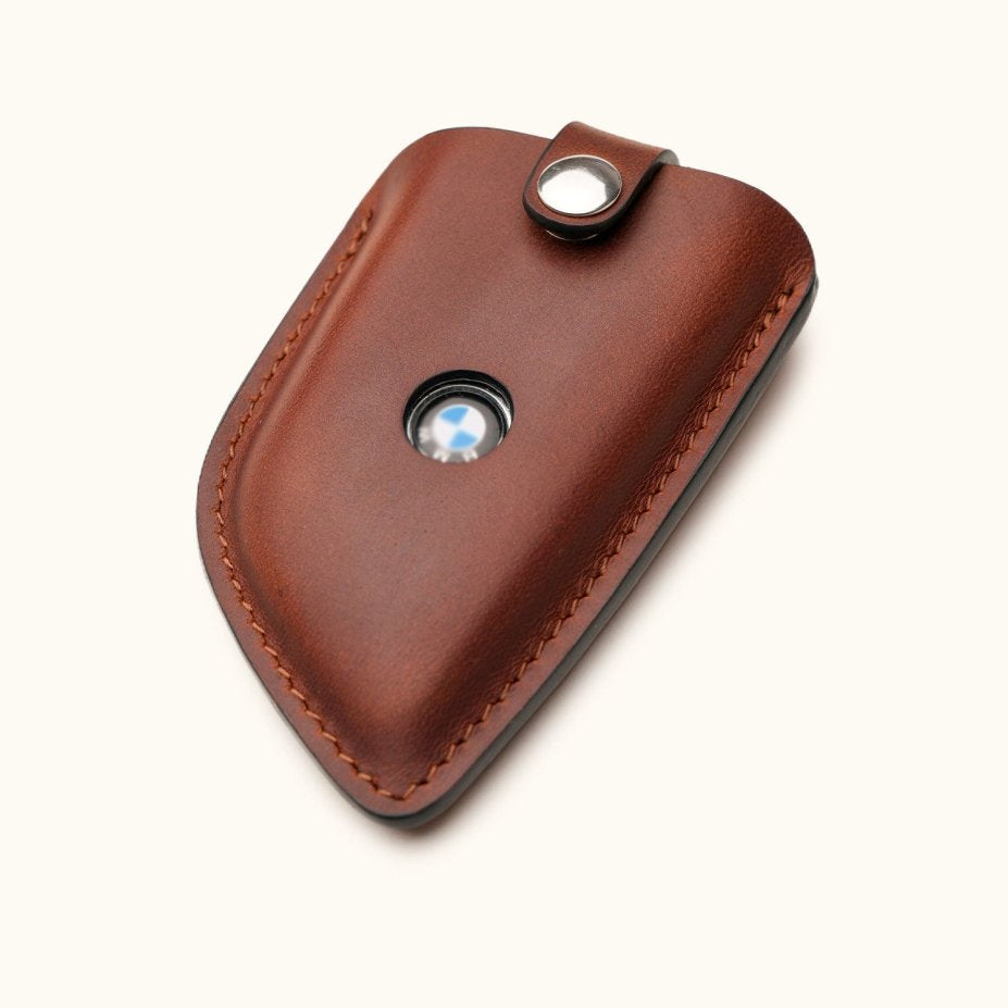 Angled view of brown leather BMW G Series smart key cover with visible logo window and snap button