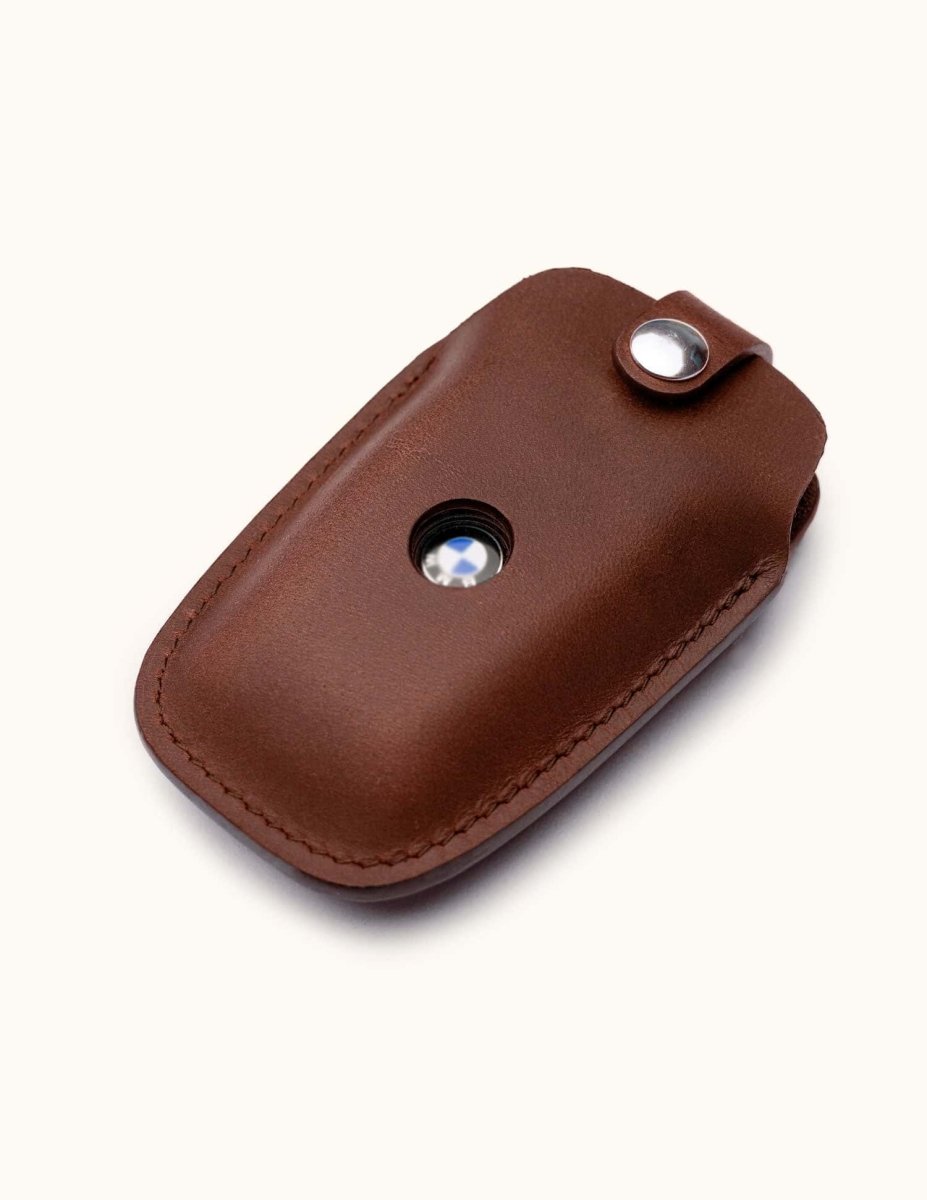 Angled view of brown leather key case for BMW car key with snap button and logo window