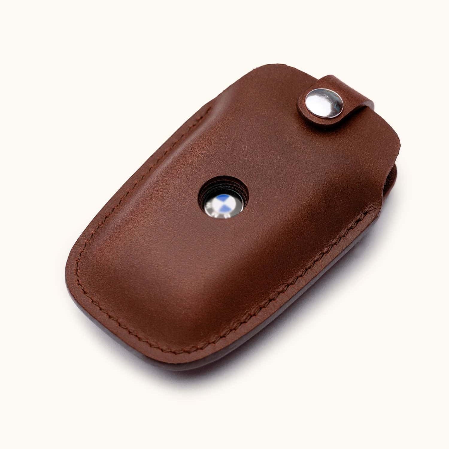 Angled view of brown leather key case for BMW car key with snap button and logo window