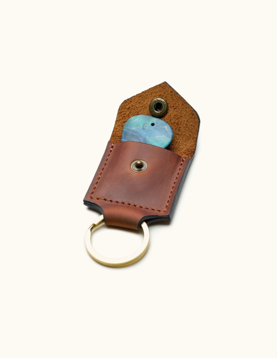 Open view of brown square leather guitar pick holder keychain with visible pick and brass snap butto