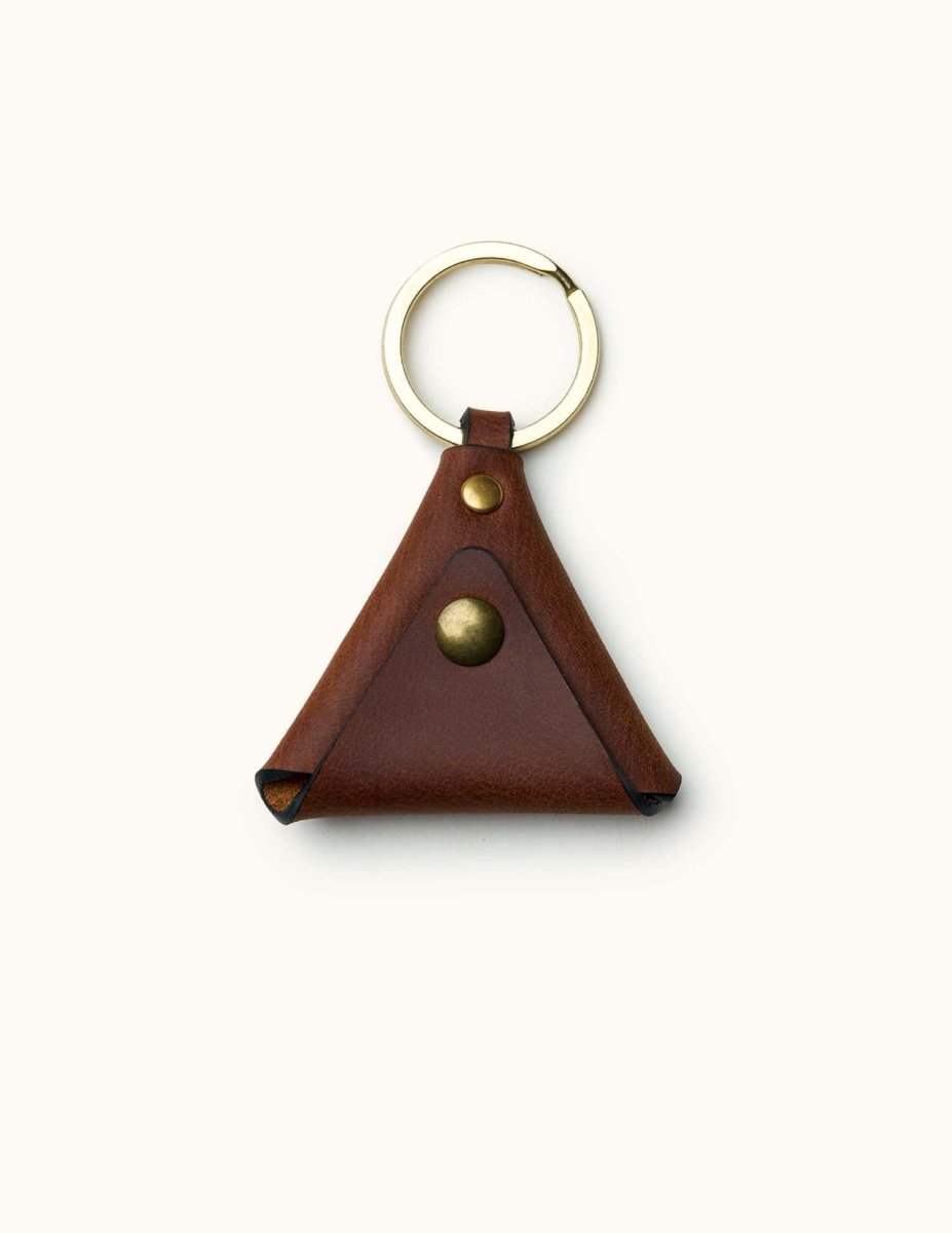 Brown triangular leather guitar pick holder with brass snap and keyring, minimalist design for musicians on the go
