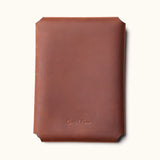 Back view of a brown full-grain leather Kindle sleeve embossed with the CraftedMan logo, showcasing the clean stitching-free design
